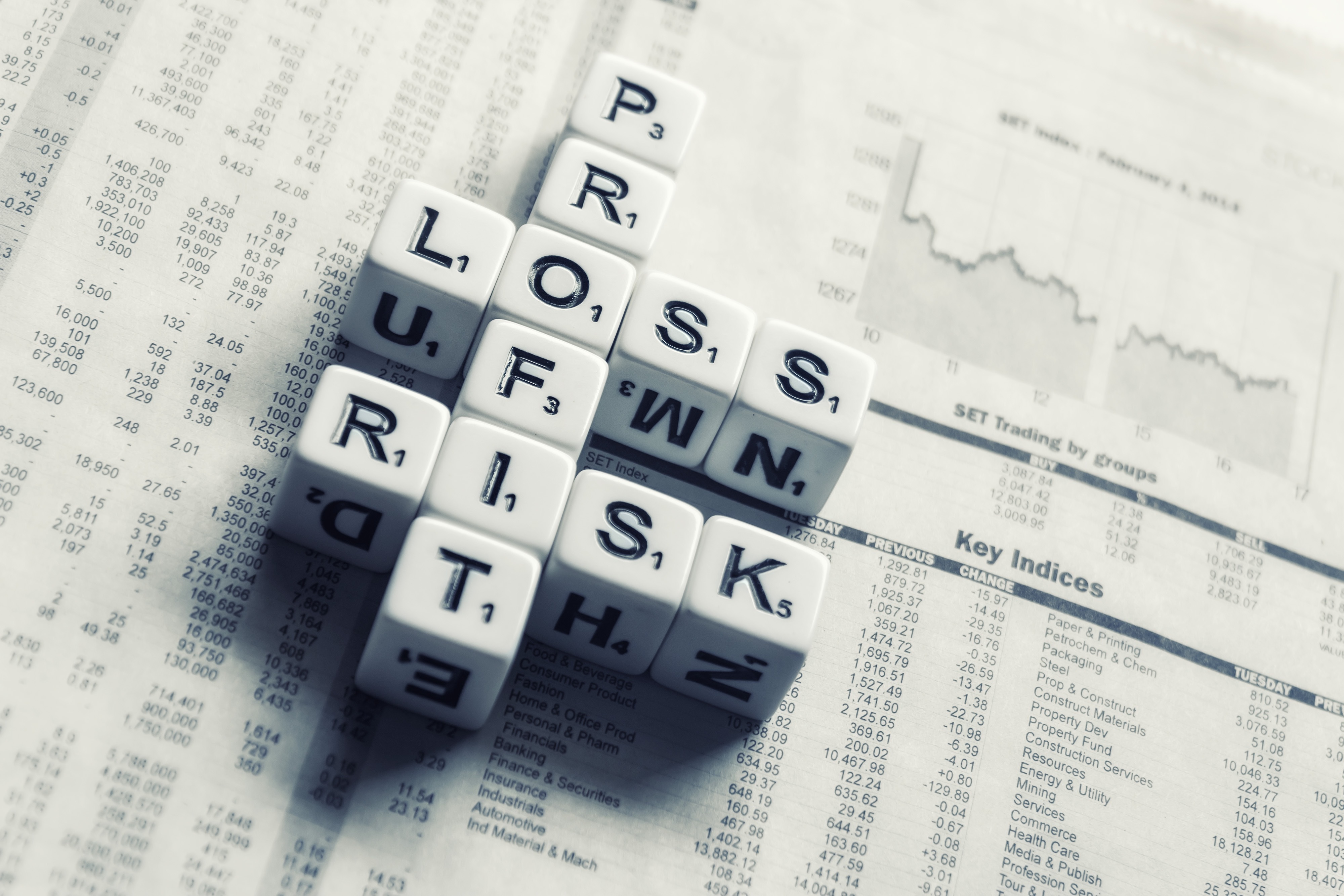 Scrabble tiles spell out words Profit, Loss, and Risk - showing how they are intertwined